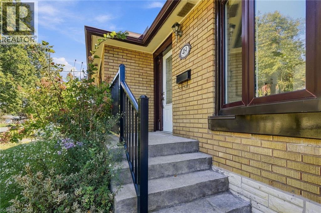 Brick exterior with concrete stairs and a black metal railing - 49 Beverly Crescent, Welland, ON