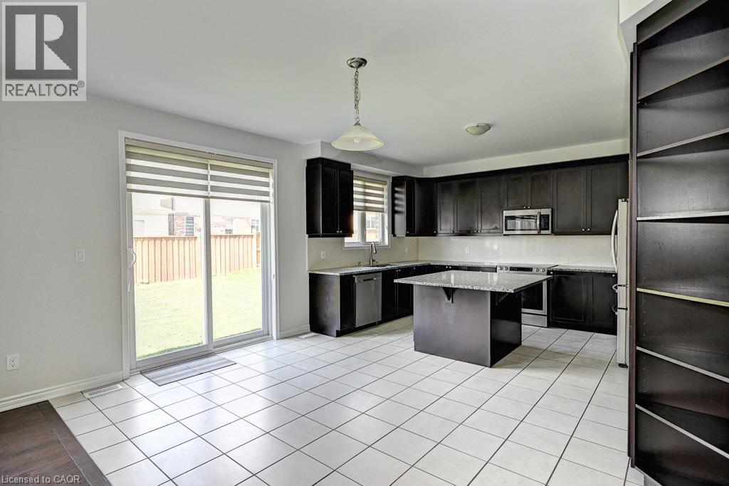 Kitchen with dark wood cabinetry, stainless steel appliances, white tile flooring, and a central island with a light-colored countertop - 236 Ridge Road, Cambridge, ON