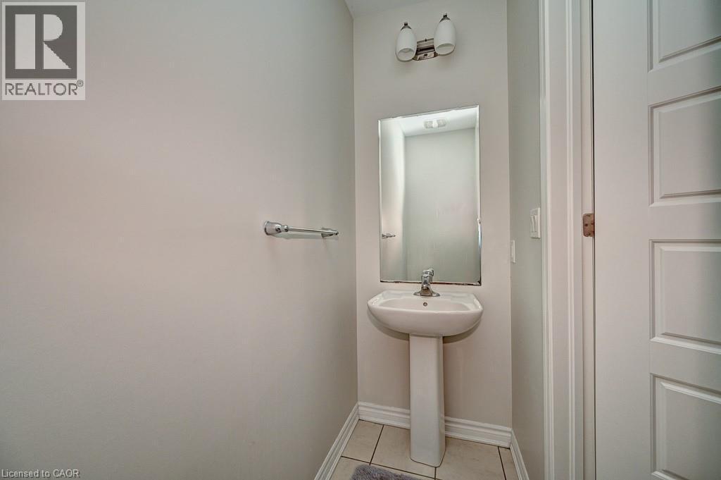 Pedestal sink with chrome faucet, wall-mounted mirror, and overhead vanity lighting - 236 Ridge Road, Cambridge, ON
