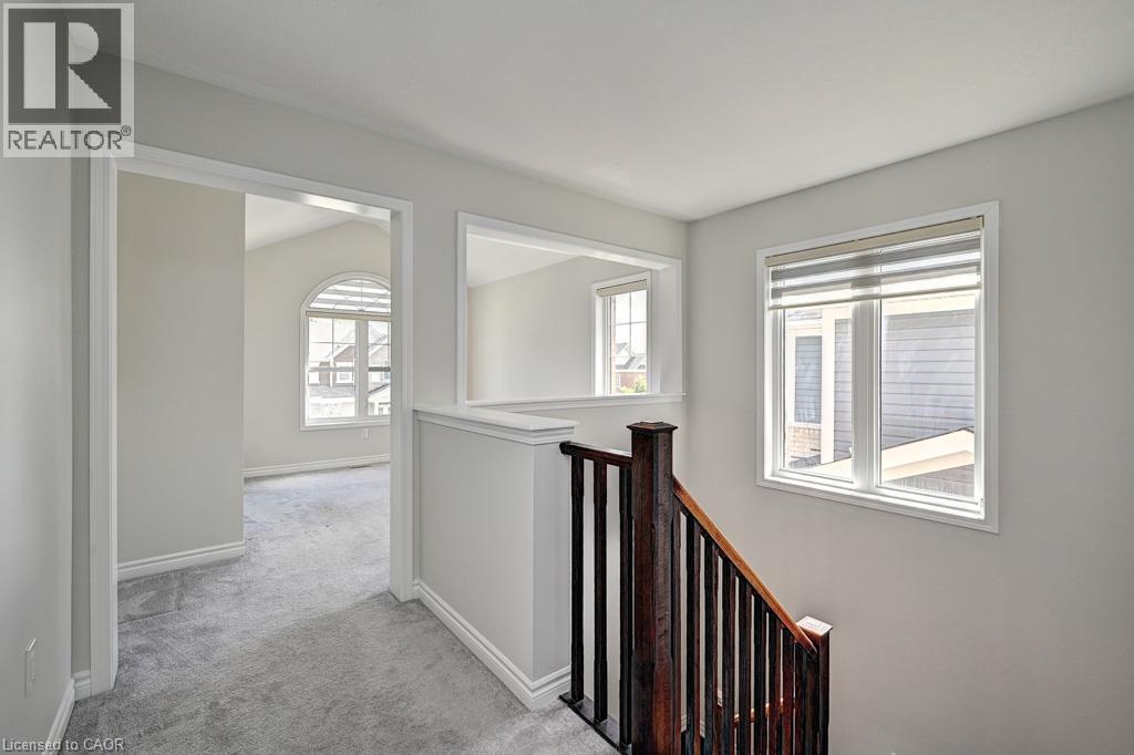 Carpeted hallway with wood staircase, white trim, and interior window feature - 236 Ridge Road, Cambridge, ON