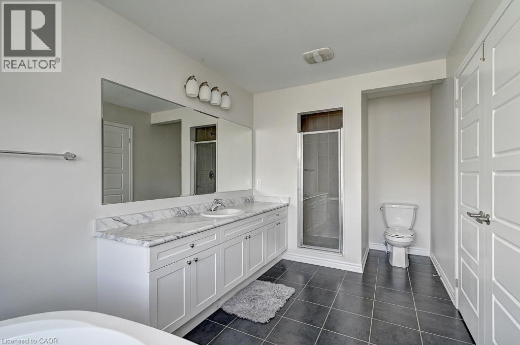 Dual vanity with a white marble-finish countertop, undermount sinks, and white shaker-style cabinetry - 236 Ridge Road, Cambridge, ON
