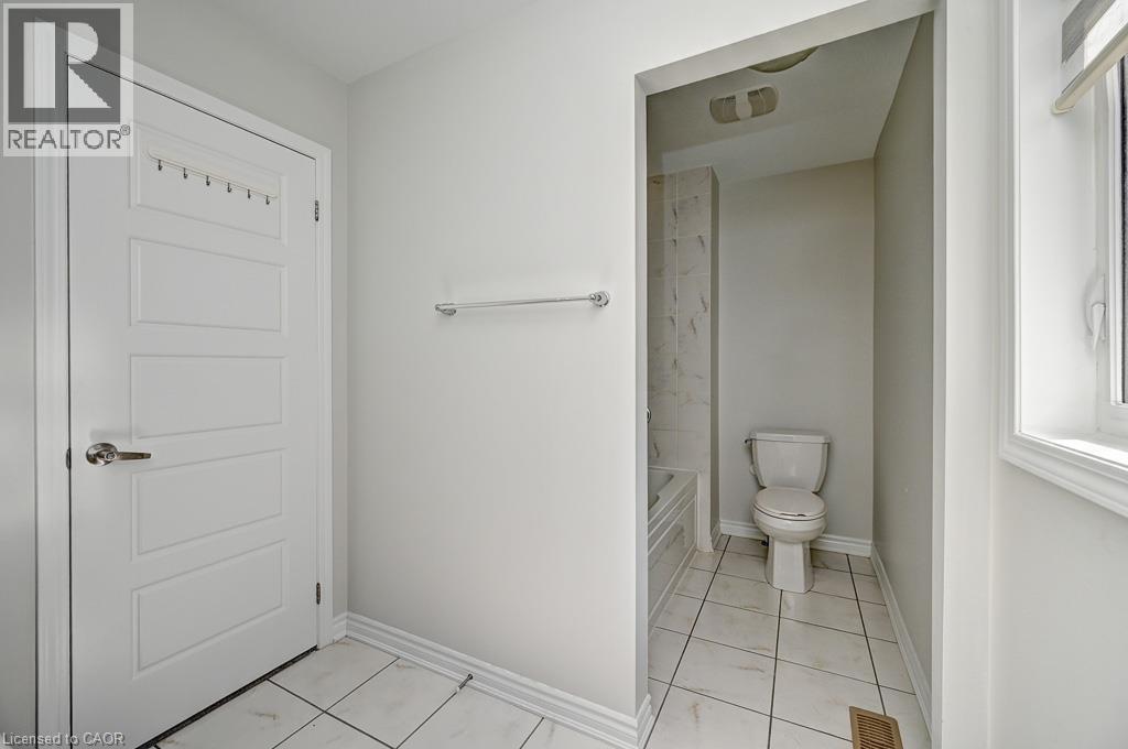 White panel door, chrome towel bar, white tile flooring, white window trim, and a built-in toilet - 236 Ridge Road, Cambridge, ON