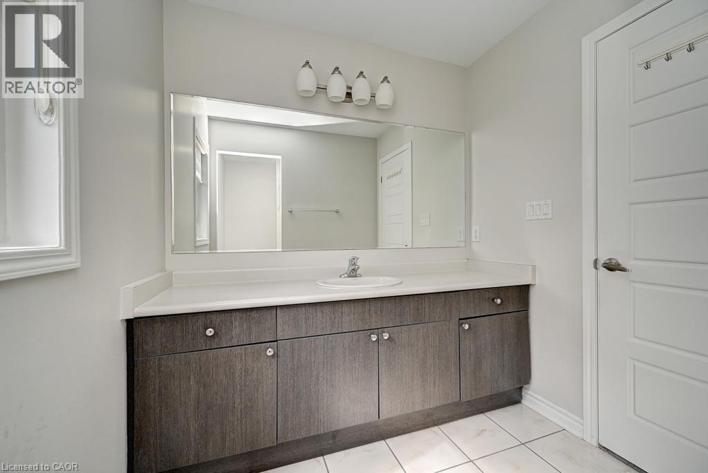 Long vanity with a single basin, wood-finish cabinetry, and a large mirror - 236 Ridge Road, Cambridge, ON