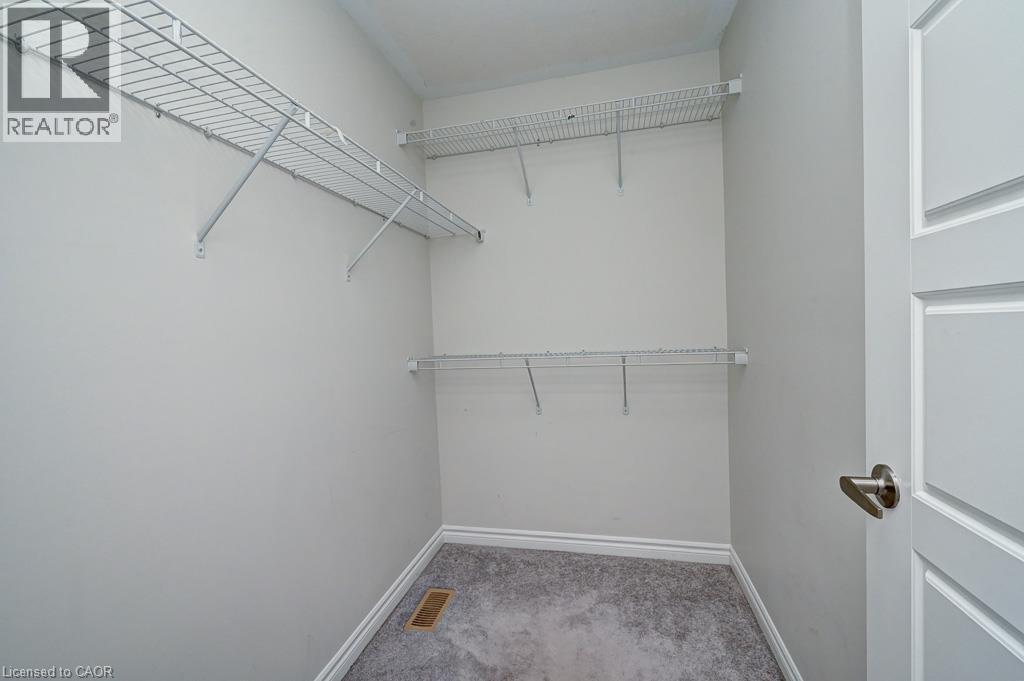 White wire shelving system, light gray wall paint, gray carpeting, white trim, and a paneled interior door with brushed nickel hardware - 236 Ridge Road, Cambridge, ON