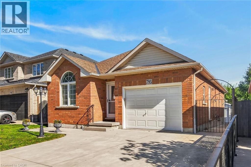 AI generated staging Brick exterior with an arched window, attached garage, concrete driveway, and wrought iron gate - 795 Tenth Avenue, Hamilton, ON