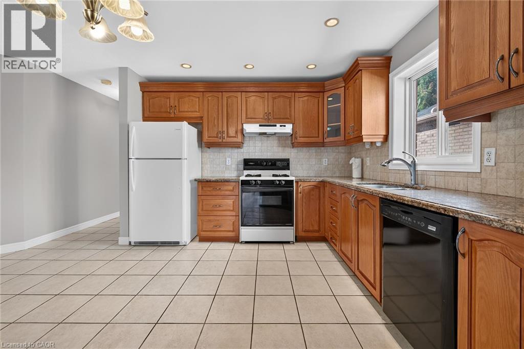 Kitchen featuring tile flooring, wood cabinetry, granite-finish countertops, stainless-steel sink, and a tile backsplash - 795 Tenth Avenue, Hamilton, ON