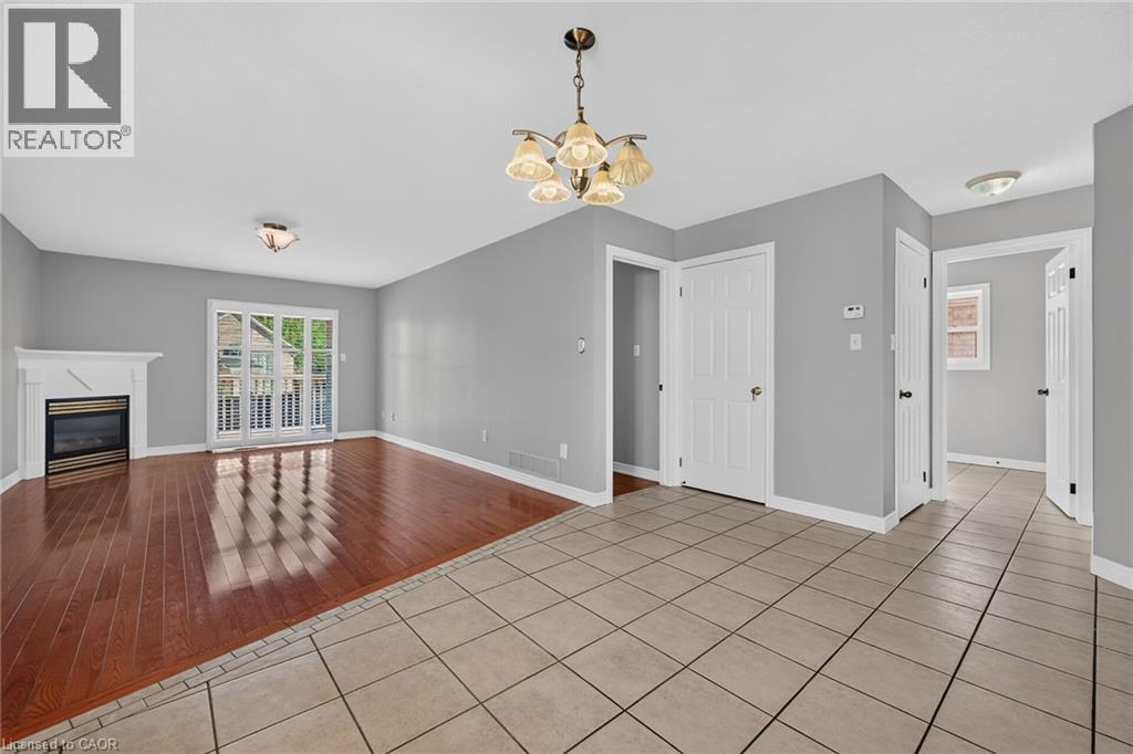 Hardwood-style flooring, fireplace with white mantel, white patio door, light gray walls, and light-toned tile flooring - 795 Tenth Avenue, Hamilton, ON