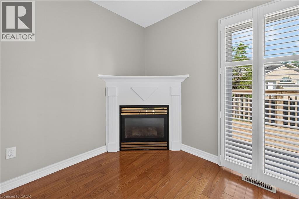 Corner fireplace with white mantel, wood-finish flooring, and white plantation shutters - 795 Tenth Avenue, Hamilton, ON