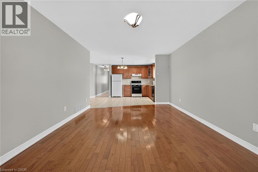 Wood-finish flooring throughout, light gray wall tones, ceiling-mounted light fixture, and a kitchen featuring wood cabinetry - 795 Tenth Avenue, Hamilton, ON