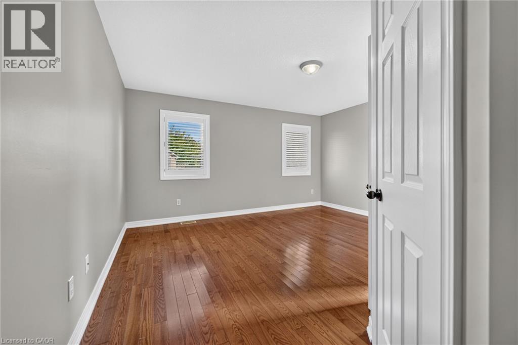 Wood-finish flooring, two windows with blinds, recessed ceiling light, paneled interior door, and light gray wall paint - 795 Tenth Avenue, Hamilton, ON