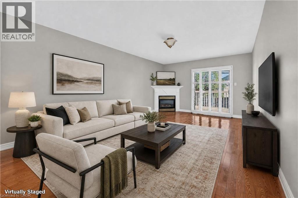 Wood-finish flooring, light gray wall paint, white fireplace with mantle, and white multi-pane glass doors - 795 Tenth Avenue, Hamilton, ON