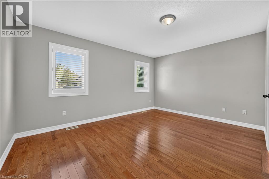 Hardwood flooring, two windows with blinds, gray wall paint, white trim, and a ceiling-mounted light fixture - 795 Tenth Avenue, Hamilton, ON