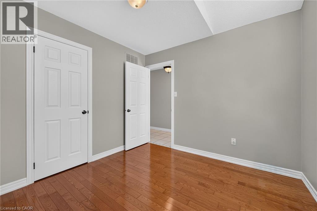 Wood-finish flooring, light gray wall paint, white trim, white six-panel interior doors, and a ceiling-mounted light fixture - 795 Tenth Avenue, Hamilton, ON