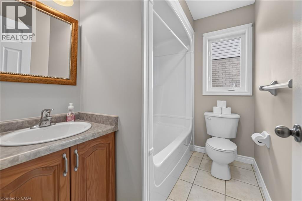 Bathroom featuring a vanity with a wood-finish cabinet, a full-size bathtub, a toilet, and ceramic tile flooring - 795 Tenth Avenue, Hamilton, ON
