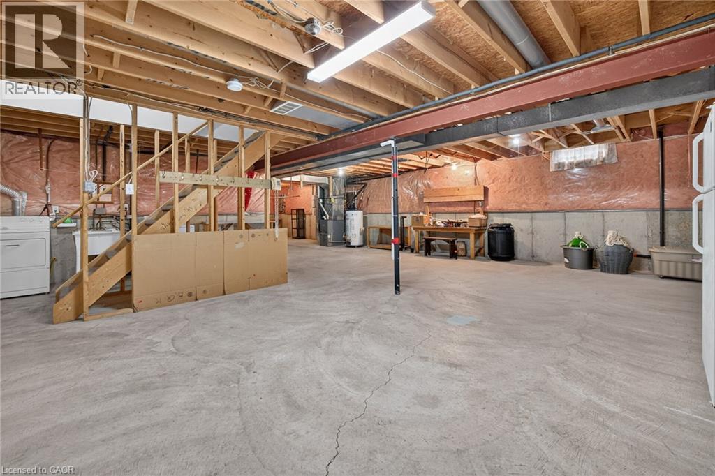 Unfinished basement with exposed ceiling joists, concrete flooring, and a utility sink - 795 Tenth Avenue, Hamilton, ON