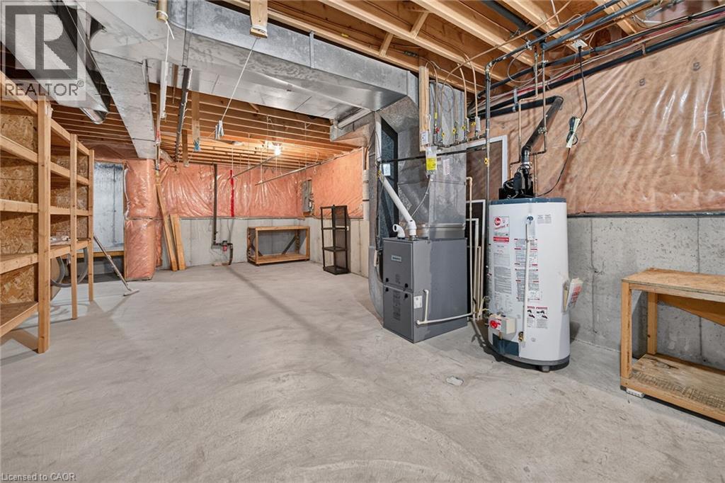 Unfinished basement with concrete flooring and exposed ceiling joists, featuring a visible water heater and furnace - 795 Tenth Avenue, Hamilton, ON