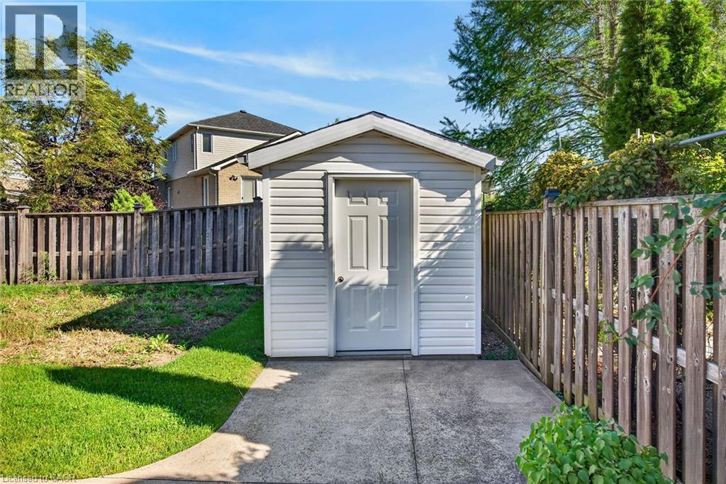Detached storage shed with siding exterior, paneled door, and concrete pad - 795 Tenth Avenue, Hamilton, ON