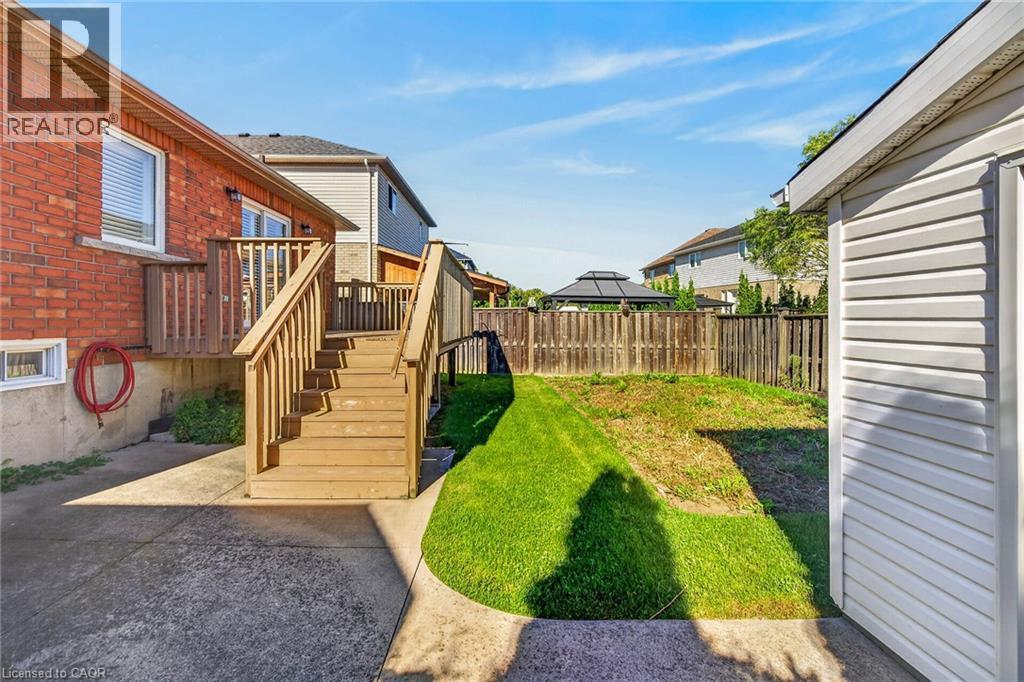 Red brick exterior with a wooden deck and stairs - 795 Tenth Avenue, Hamilton, ON