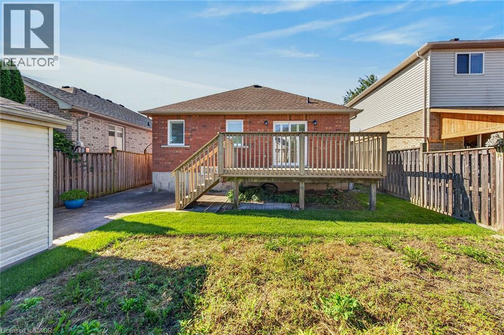 Brick exterior with a wood deck, sliding glass doors, white trim windows, and a detached shed - 795 Tenth Avenue, Hamilton, ON