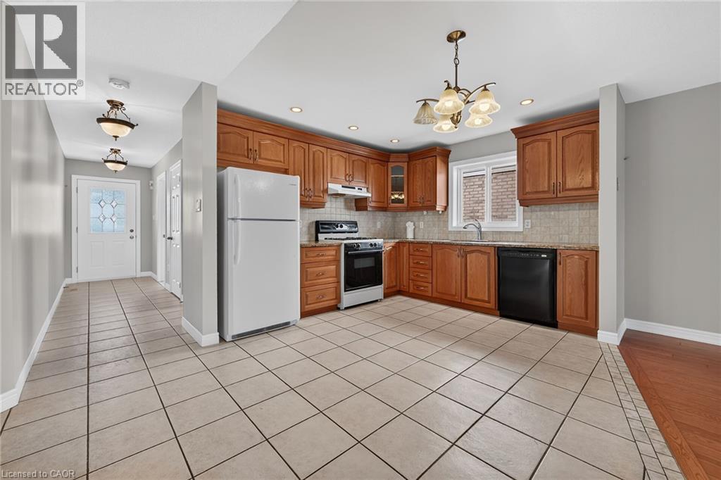 Kitchen featuring wood-finish cabinetry, tile flooring, and integrated appliances - 795 Tenth Avenue, Hamilton, ON