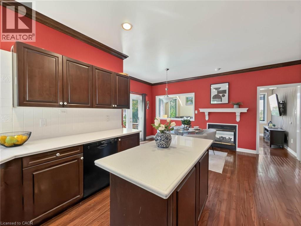 Kitchen featuring dark wood cabinetry, white countertops, white tile backsplash, and a central island - 74 Davidson Boulevard, Dundas, ON