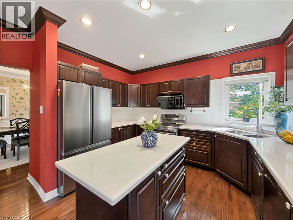 Kitchen featuring rich wood cabinetry, stainless steel appliances, a center island with a light-toned countertop, and recessed lighting - 74 Davidson Boulevard, Dundas, ON