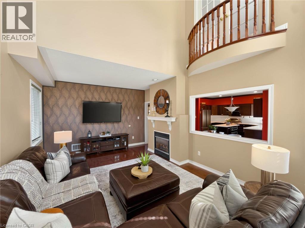 Two-story living area with a built-in fireplace, wood-finish flooring, and an interior balcony - 74 Davidson Boulevard, Dundas, ON