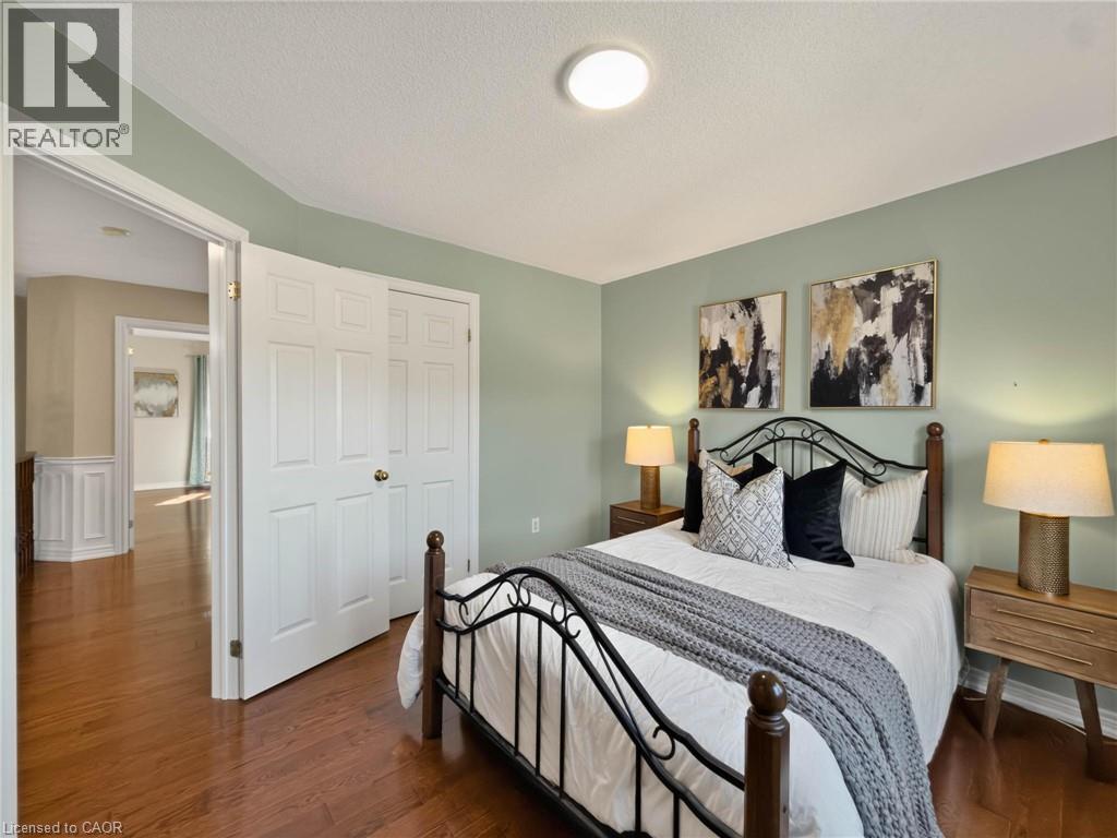 Hardwood flooring, neutral wall color, built-in closet, round ceiling light fixture, and white paneled doors - 74 Davidson Boulevard, Dundas, ON