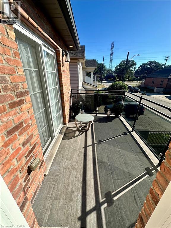 Balcony with tile flooring, glass railing, brick exterior, and sliding glass door access - 5 Arden Avenue, Hamilton, ON