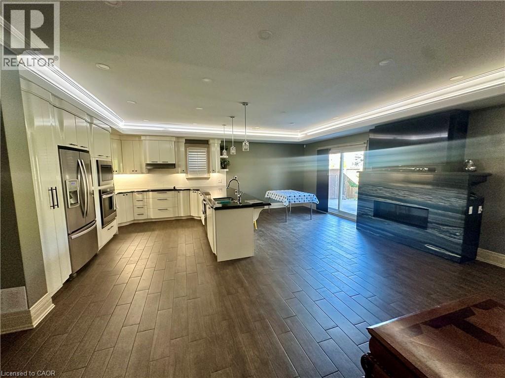 Gourmet kitchen with stainless steel appliances, central island, and wood-finish flooring - 5 Arden Avenue, Hamilton, ON