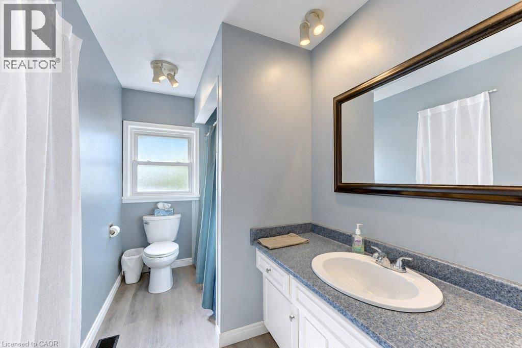 Vanity with integrated sink, wood-finish flooring, framed mirror, and track lighting - 34 Wayne Drive, Kitchener, ON