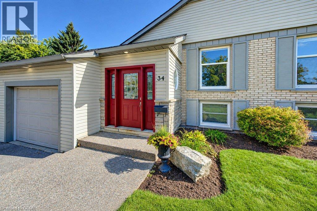 Brick and siding exterior with gray shutters, front door with sidelights, attached garage, and a concrete driveway - 34 Wayne Drive, Kitchener, ON