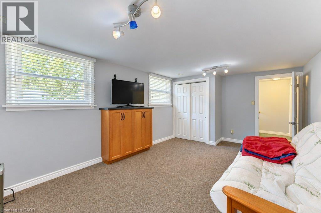 Recessed windows with blinds, built-in wood-finish cabinetry, neutral carpeting, and track lighting - 34 Wayne Drive, Kitchener, ON