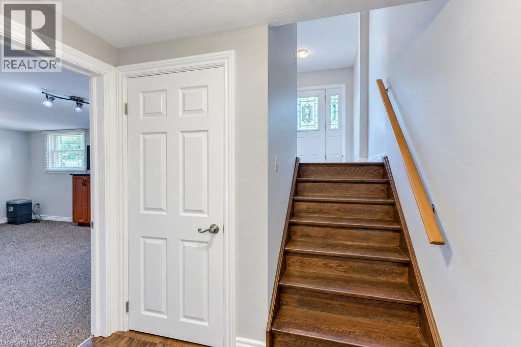 Hardwood staircase with natural wood handrail, paneled interior door, and front entry door with decorative glass inserts - 34 Wayne Drive, Kitchener, ON
