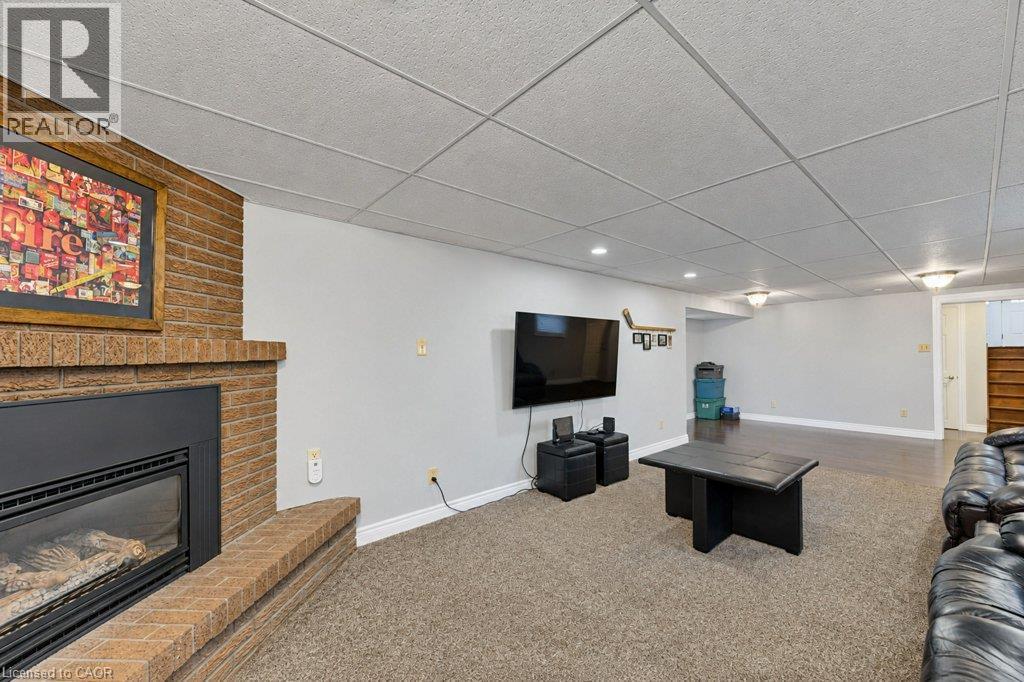 Brick-clad gas fireplace with a gas insert, recessed lighting, drop ceiling, and carpeted flooring - 34 Wayne Drive, Kitchener, ON