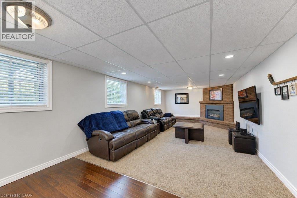 Recessed lighting, brick fireplace with mantel, two windows, wood-finish flooring, and carpeted area - 34 Wayne Drive, Kitchener, ON