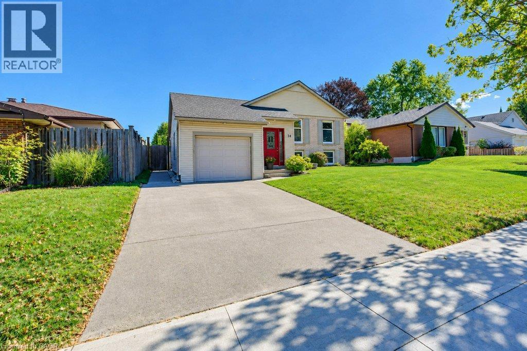 Lovely curb appeal featuring a single-car garage, concrete driveway, and a red entry door - 34 Wayne Drive, Kitchener, ON