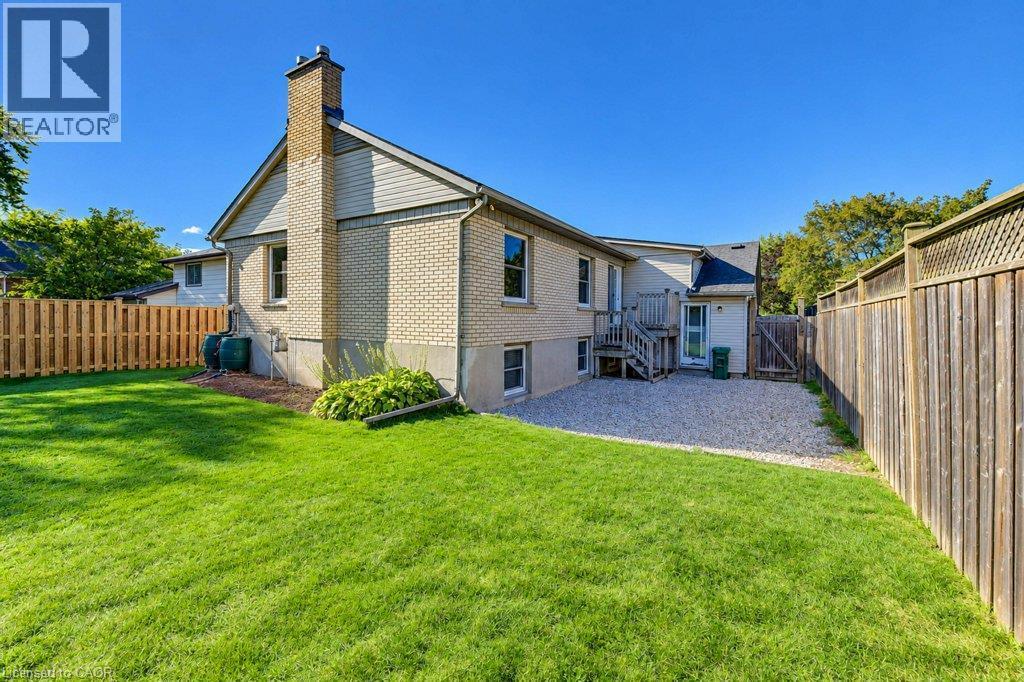 Brick exterior with a prominent chimney, wood-paneled siding, and a rear wooden deck - 34 Wayne Drive, Kitchener, ON