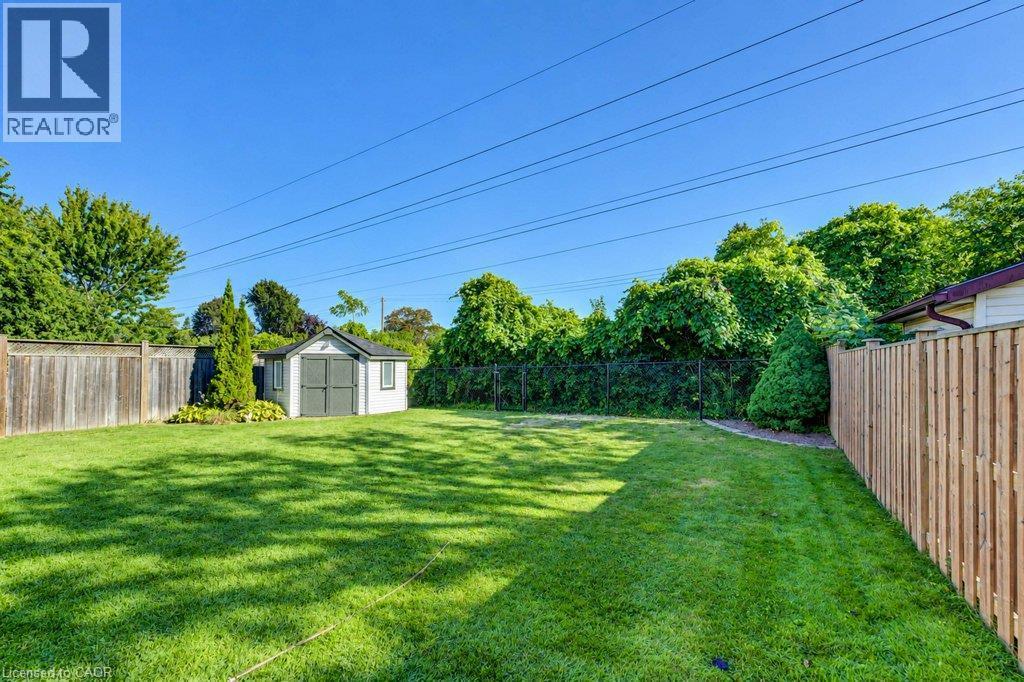 Expansive backyard featuring a manicured lawn, a detached storage shed, privacy fencing, and mature perimeter trees - 34 Wayne Drive, Kitchener, ON