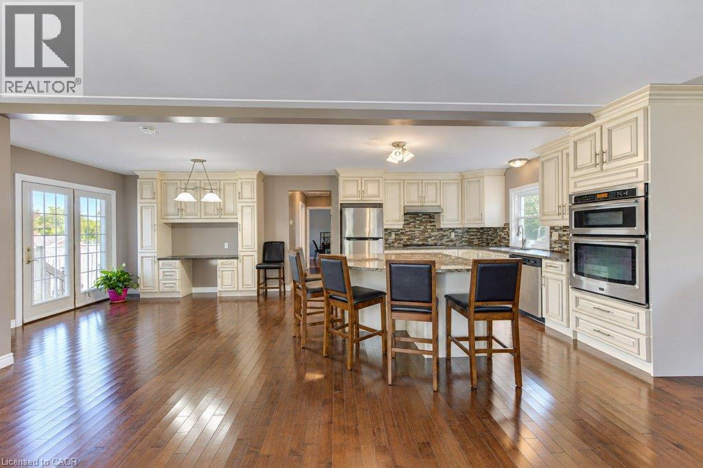 Bright open-concept kitchen with wood-finish flooring, light-toned cabinetry, stainless steel appliances, and a central island with a stone-finish countertop - 34 Wayne Drive, Kitchener, ON