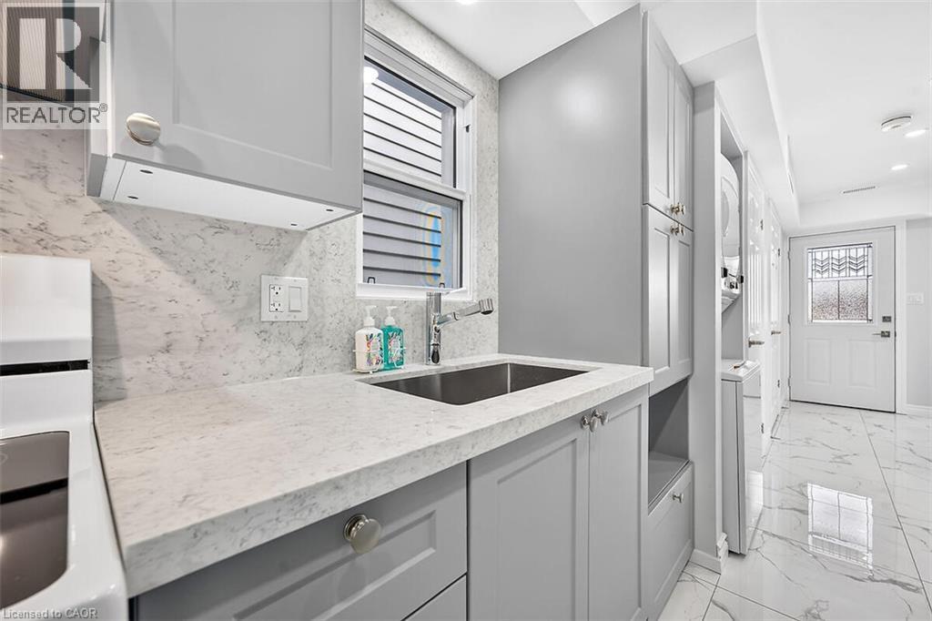 Light gray cabinetry, integrated sink, stone-finish countertop, coordinating backsplash, and tile flooring - 4 Albemarle Street, Hamilton, ON