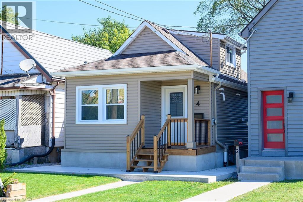 Siding exterior with white trim, covered front porch, and wood stairs with black railings - 4 Albemarle Street, Hamilton, ON