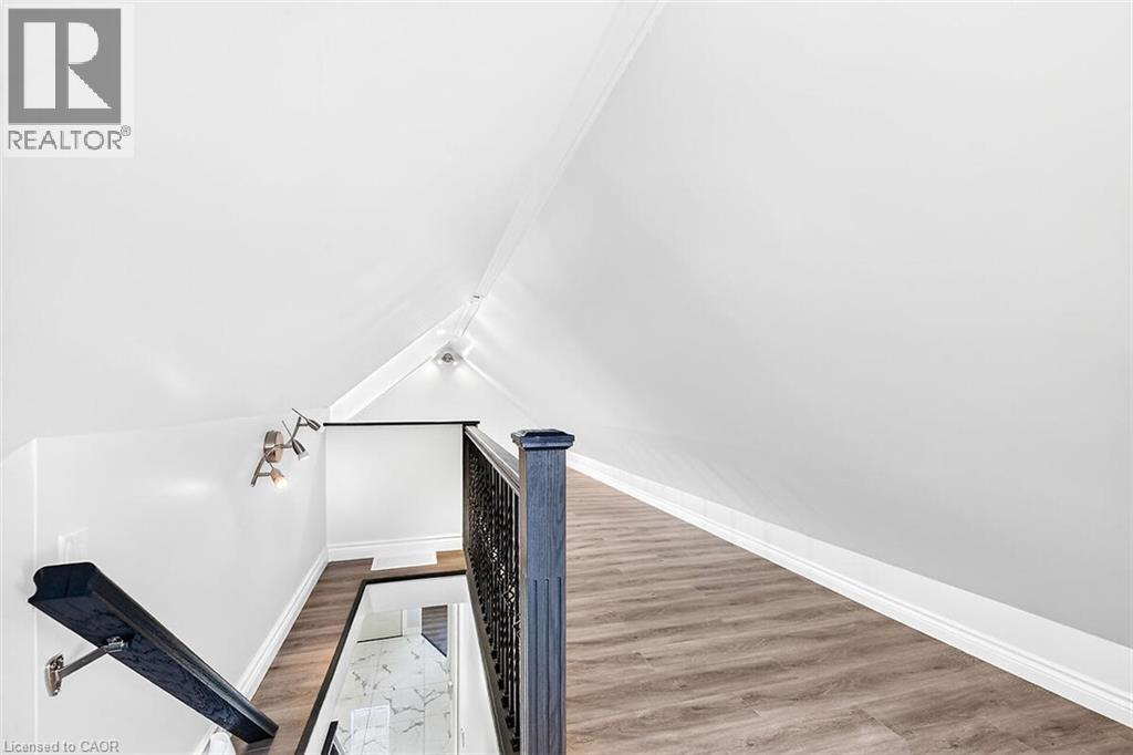 Upper-level landing with wood-finish flooring, recessed lighting, track lighting, and a dark wood newel post - 4 Albemarle Street, Hamilton, ON