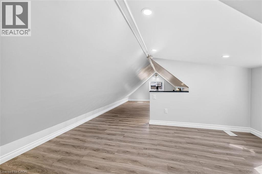 Sloped ceiling with recessed lighting, wood-finish flooring, white walls, and built-in counter space - 4 Albemarle Street, Hamilton, ON