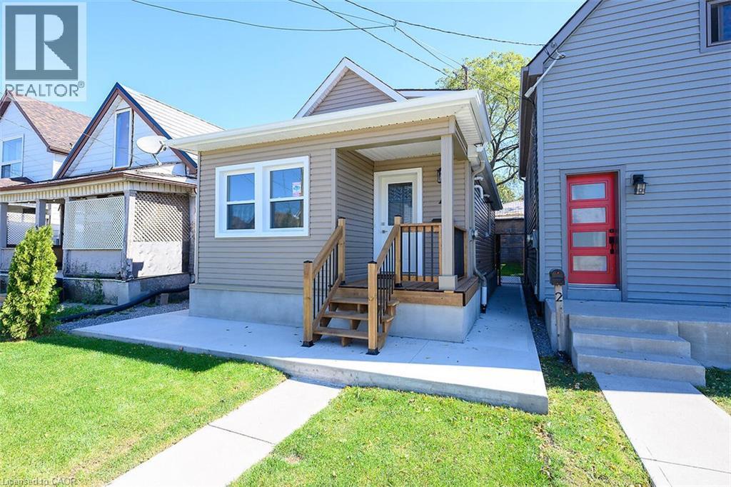 Front facade with horizontal siding, covered porch, and exterior lighting - 4 Albemarle Street, Hamilton, ON