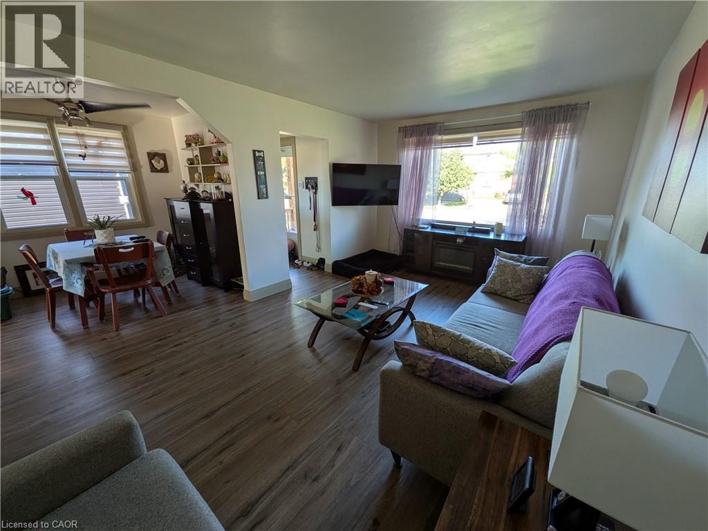 Wood-finish flooring throughout, living area with large window, and dining area featuring an angled ceiling with a ceiling fan - 487 Scholfield Avenue N, Welland, ON