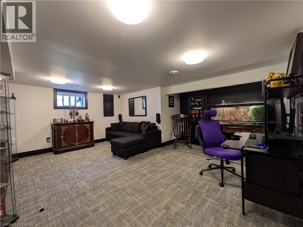 Carpeted flooring provides comfort throughout this spacious room, illuminated by multiple ceiling-mounted fixtures - 487 Scholfield Avenue N, Welland, ON