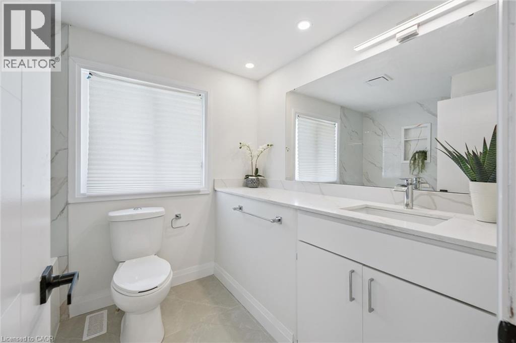 Contemporary bathroom featuring a white vanity with an integrated sink, polished chrome faucet, and expansive wall-mounted mirror - 299 Dale Crescent, Waterloo, ON
