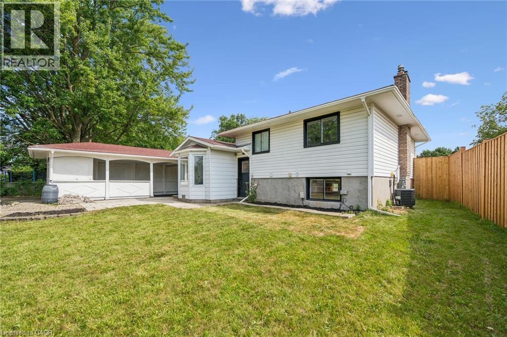 Rear exterior featuring white siding, a brick chimney, and a bay window - 299 Dale Crescent, Waterloo, ON