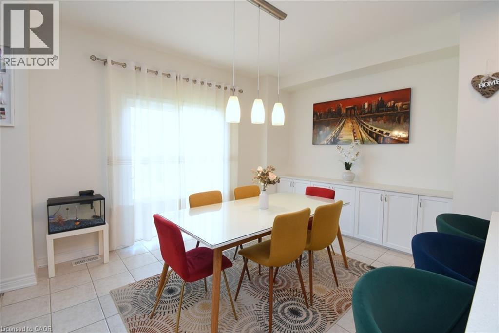 Recessed built-in cabinetry with white doors and a light-toned countertop, modern pendant light fixture, tiled flooring, expansive window with sheer curtains, and light-toned walls - 25 Guest Street, Hamilton, ON
